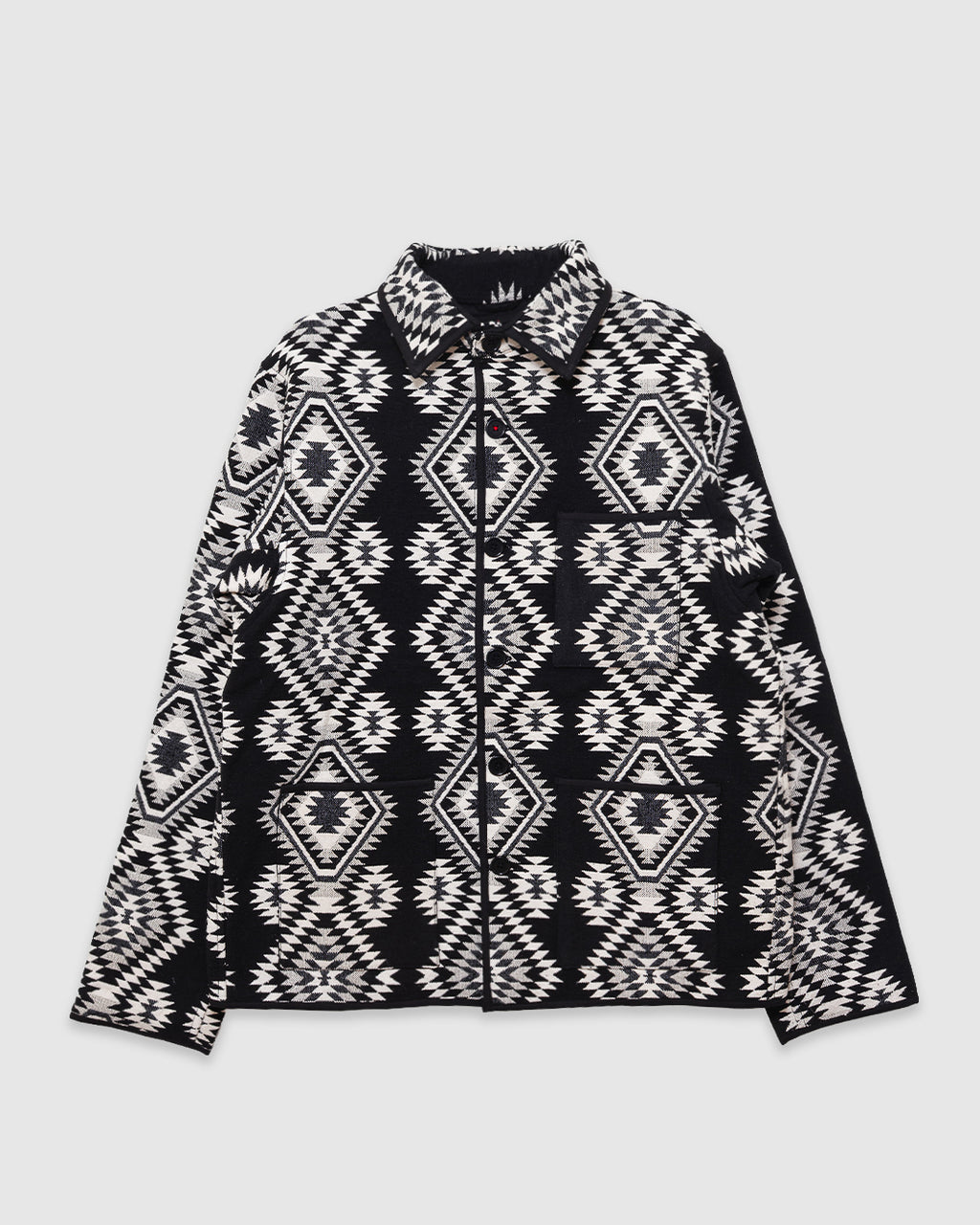 A black and white patterned zip-up jacket with a geometric tribal design, laid flat against a light gray background.