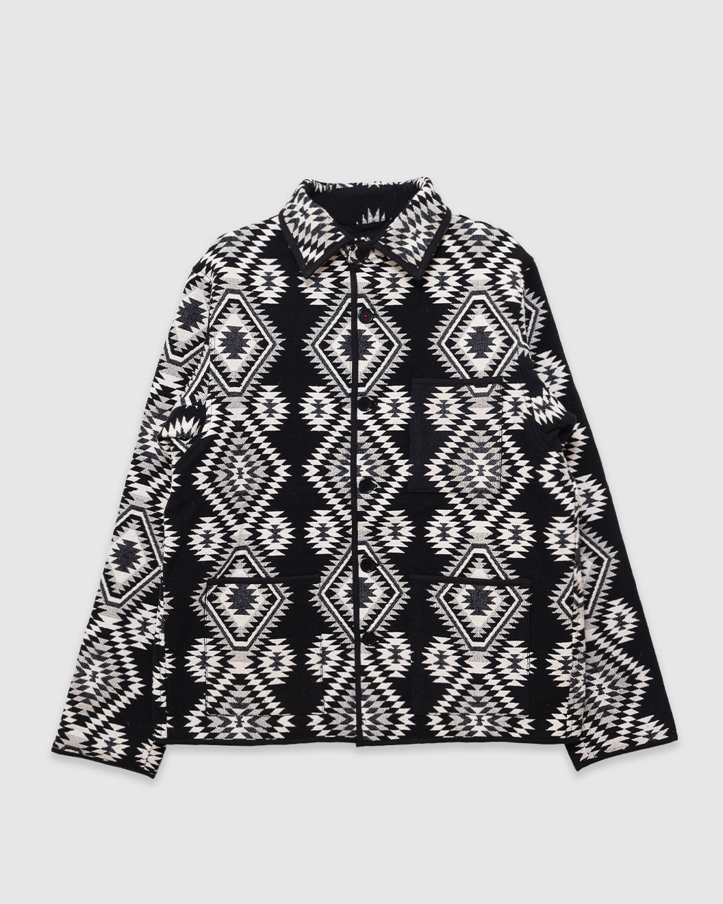 A black and white patterned zip-up jacket with a geometric tribal design, laid flat against a light gray background.